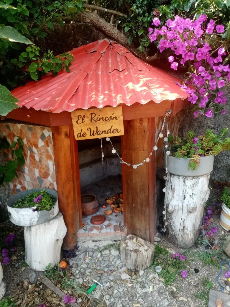 El Rincón de Wander, una pequeña casita de madera entre flores del jardín de Elfen